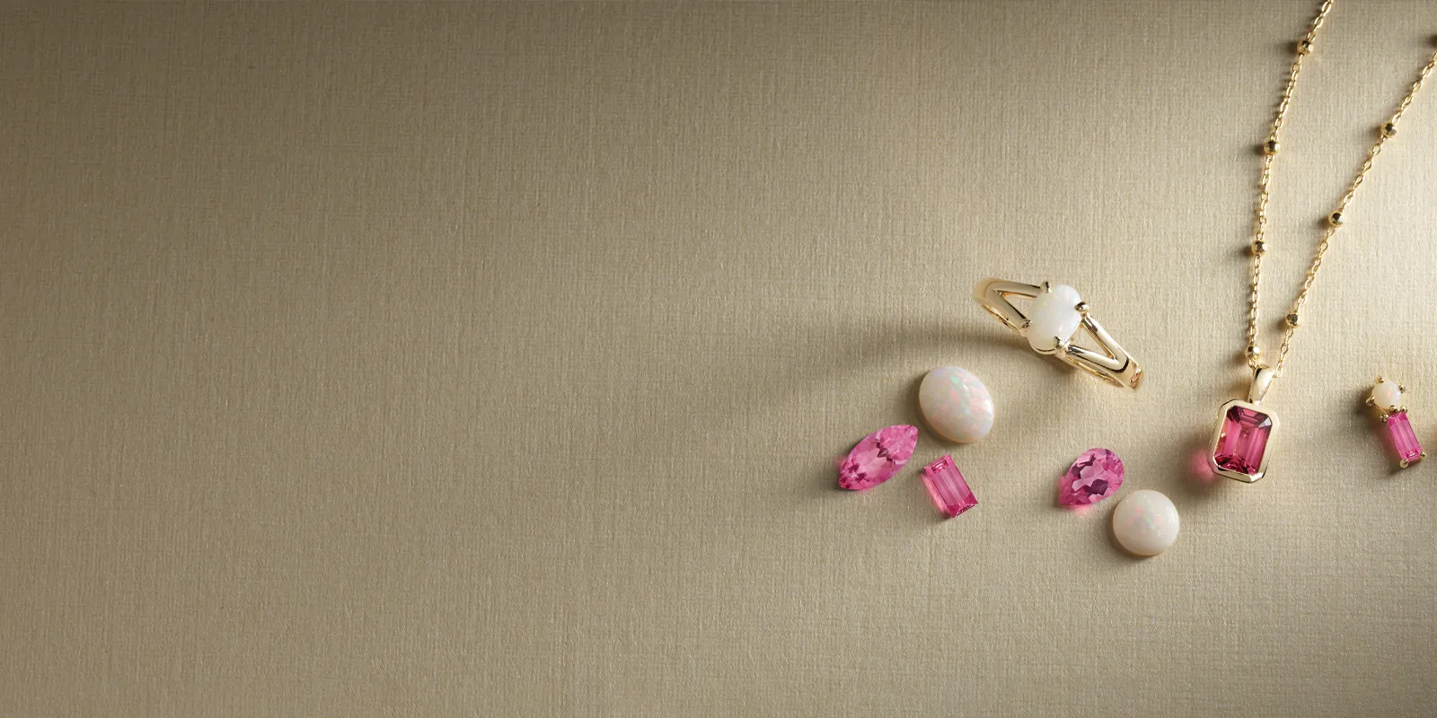 Elegant jewelry pieces featuring pink gemstones and gold accents, promoting birthstone jewelry.