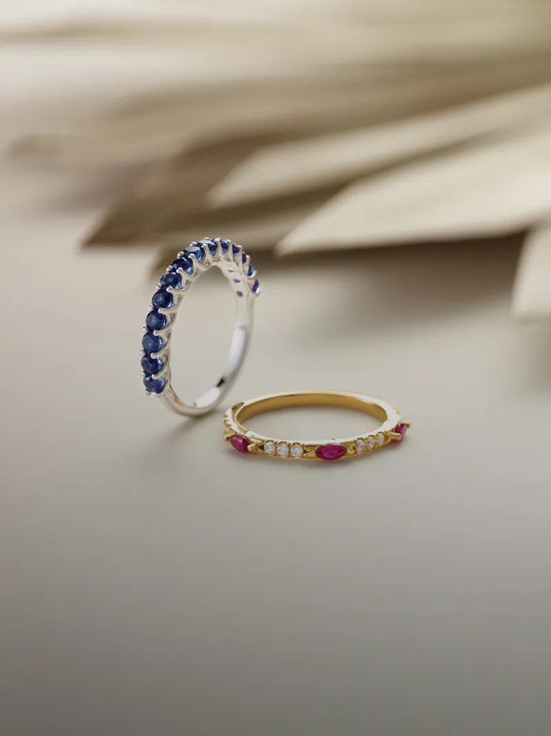 Two elegant rings: a silver band with blue stones and a gold band with pink stones and diamonds.