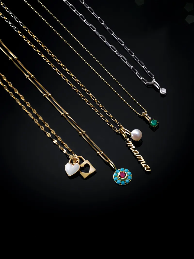 Gold and silver necklaces with charms, including hearts, a pearl, and 