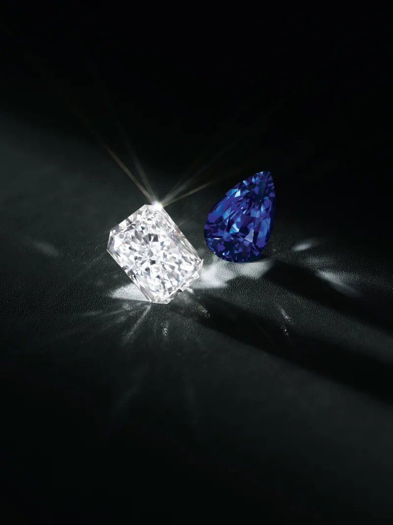 A sparkling white diamond and a blue gemstone on a dark background, showcasing their brilliance.