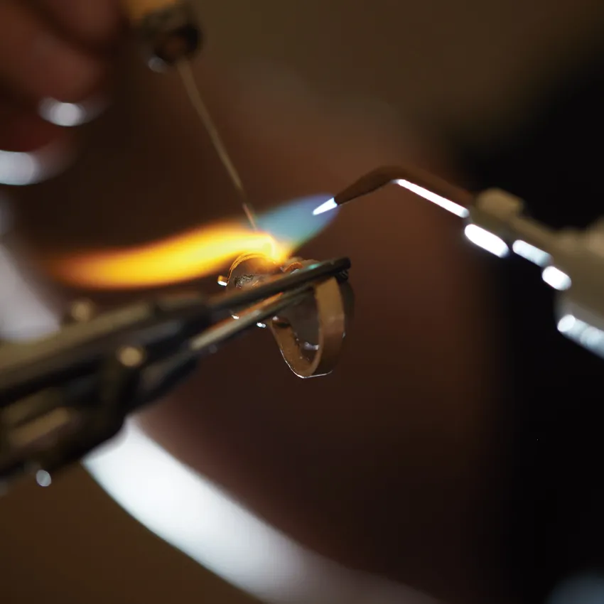 Jeweler using a torch to heat a ring, showcasing the craftsmanship.