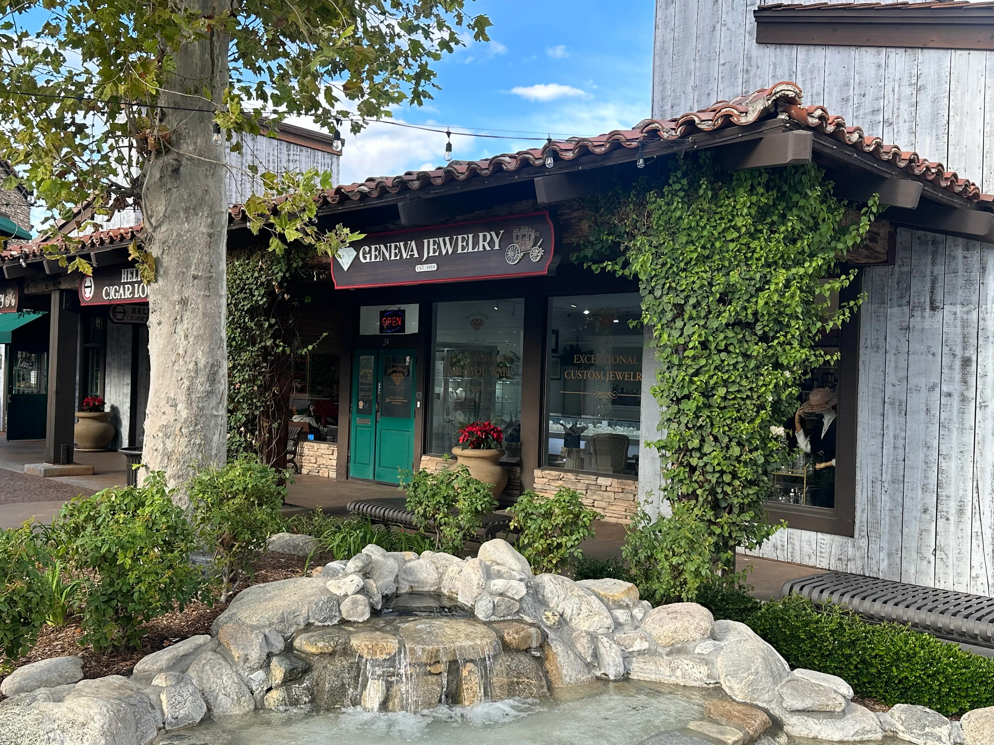 Geneva Jewelry storefront in Riverside, featuring a fountain and greenery, with an