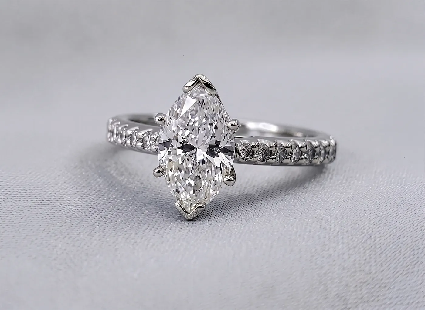Marquise diamond ring with pavé band on a light background.