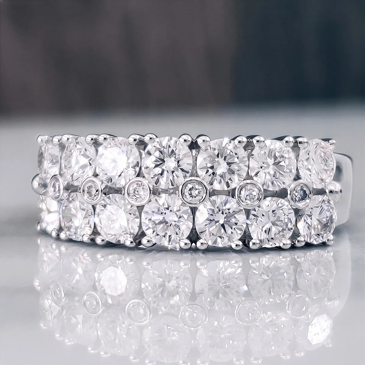 Elegant diamond ring with multiple rows of round stones on a reflective surface.