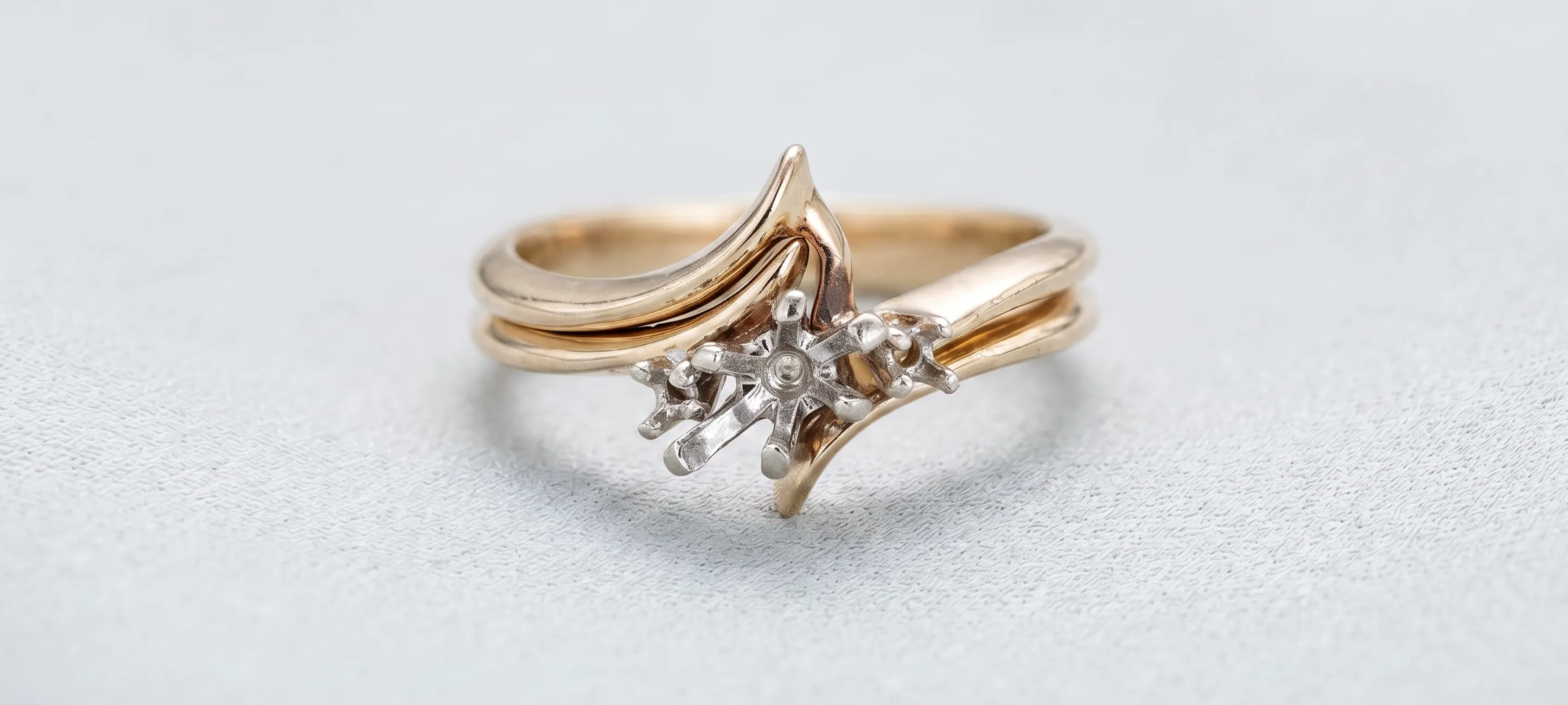 Gold ring with a unique design featuring a star-like silver accent. Click to start a project.