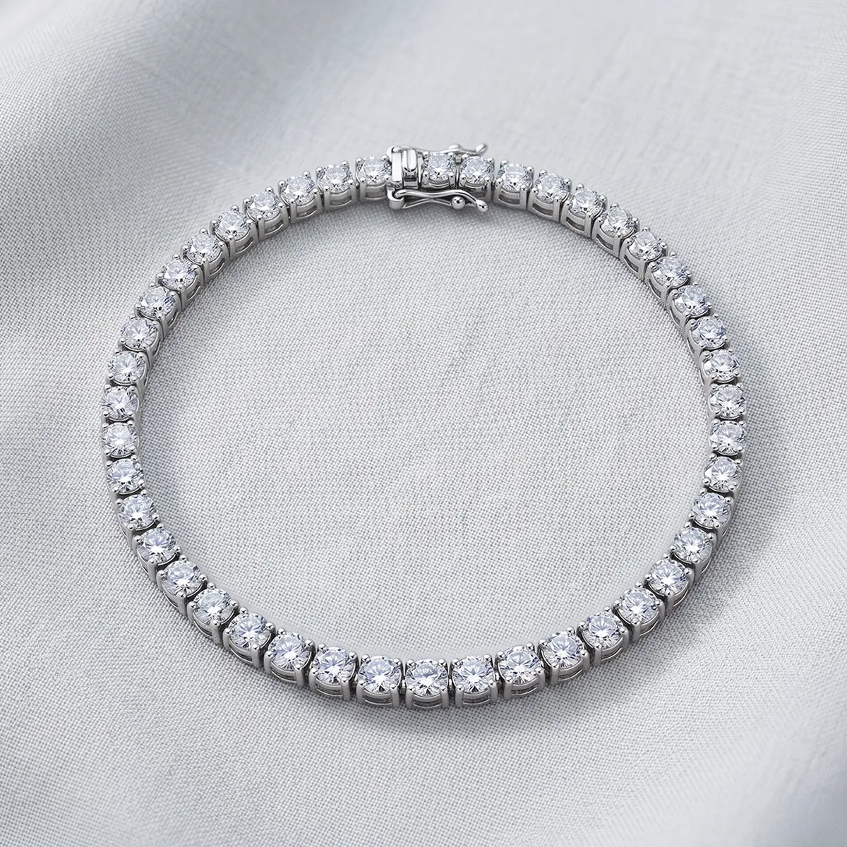 Elegant diamond tennis bracelet on a light fabric background.
