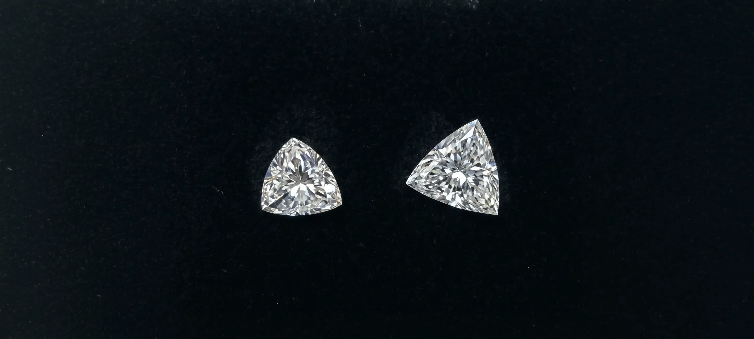Two triangular diamonds on a black background. Click to shop lab diamonds.