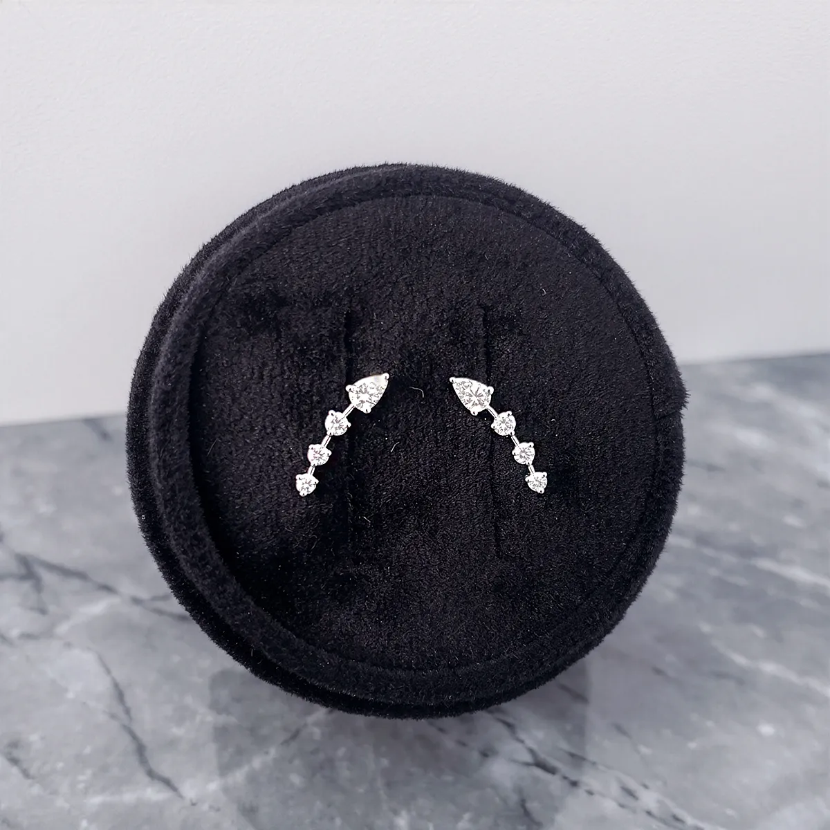Diamond earrings with arrow design on black velvet display.