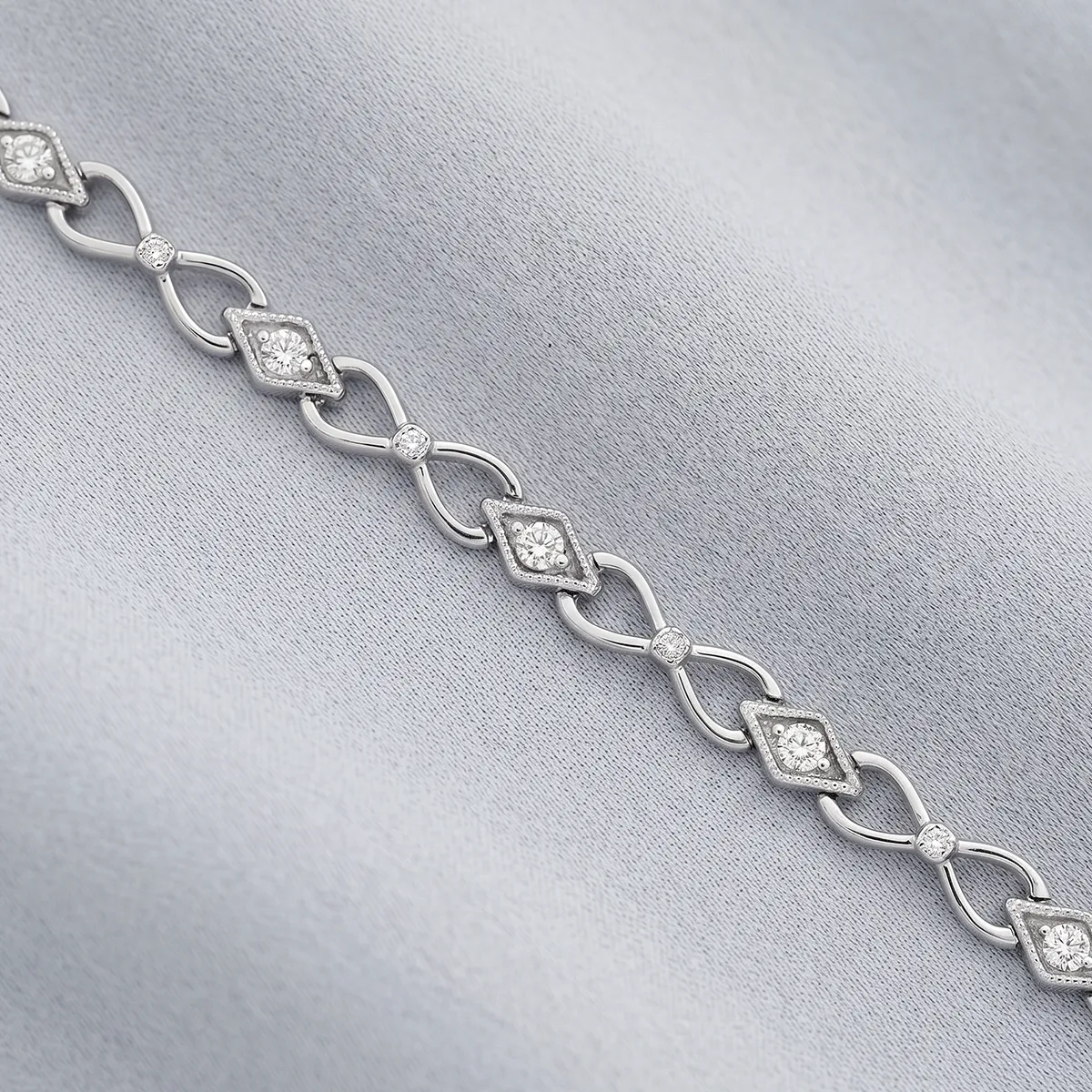 Elegant diamond bracelet with intricate design on a soft gray fabric background.