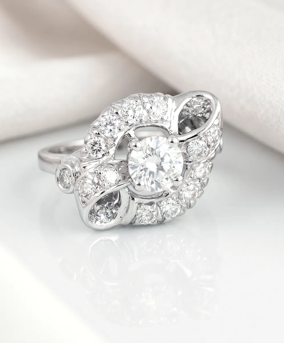 Elegant diamond ring with intricate design on a white surface.