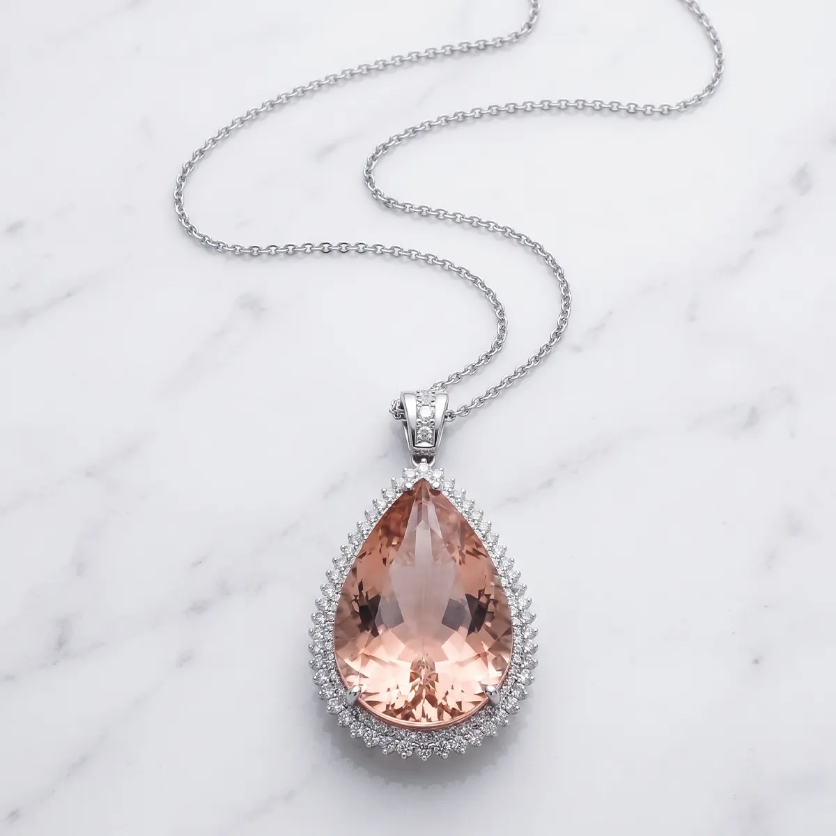 Teardrop peach gemstone pendant with diamond halo on silver chain. Explore estate necklaces and pendants.