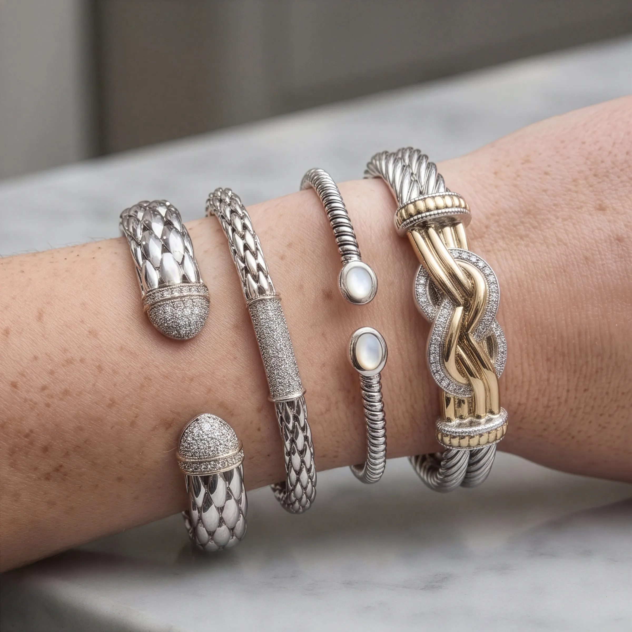 Silver and gold bracelets on a wrist. Explore silver estate jewelry at Georgetown Jewelers.