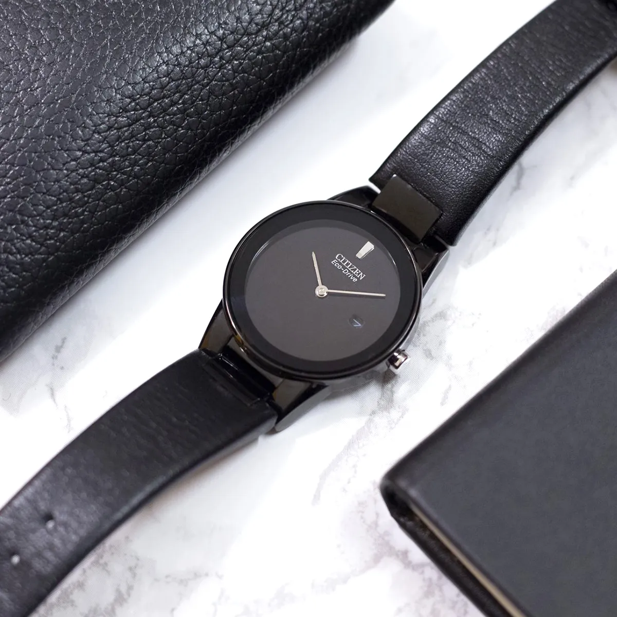 Sleek black Citizen Eco-Drive watch with leather strap on marble surface. View all watches at Georgetown Jewelers.