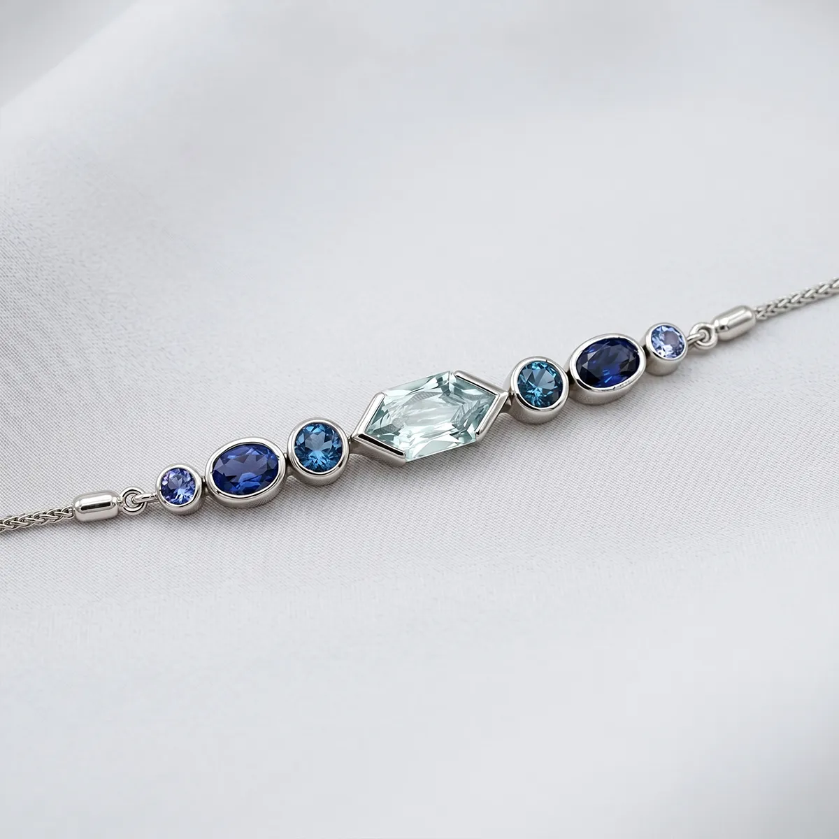 A bracelet with blue gemstones set in silver on a light background.