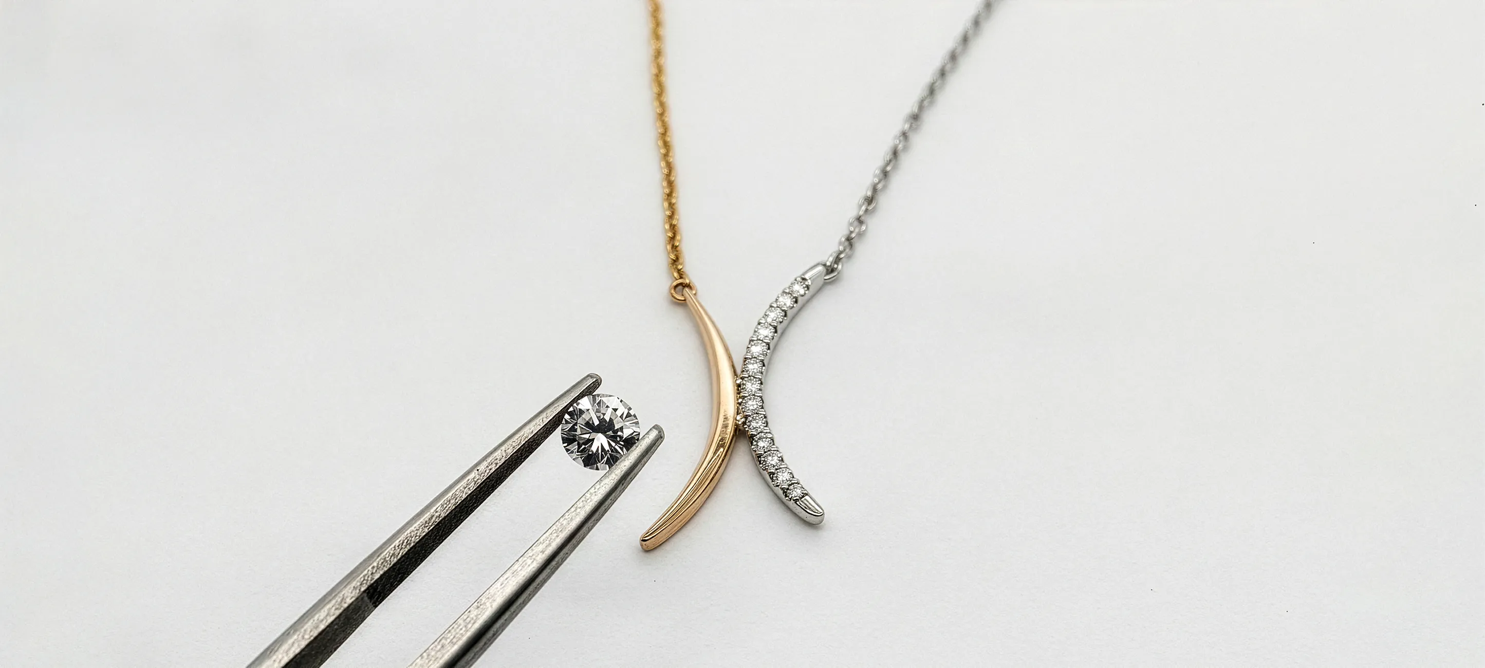 Two necklaces with curved pendants and a diamond held by tweezers. Explore our services at Georgetown Jewelers.