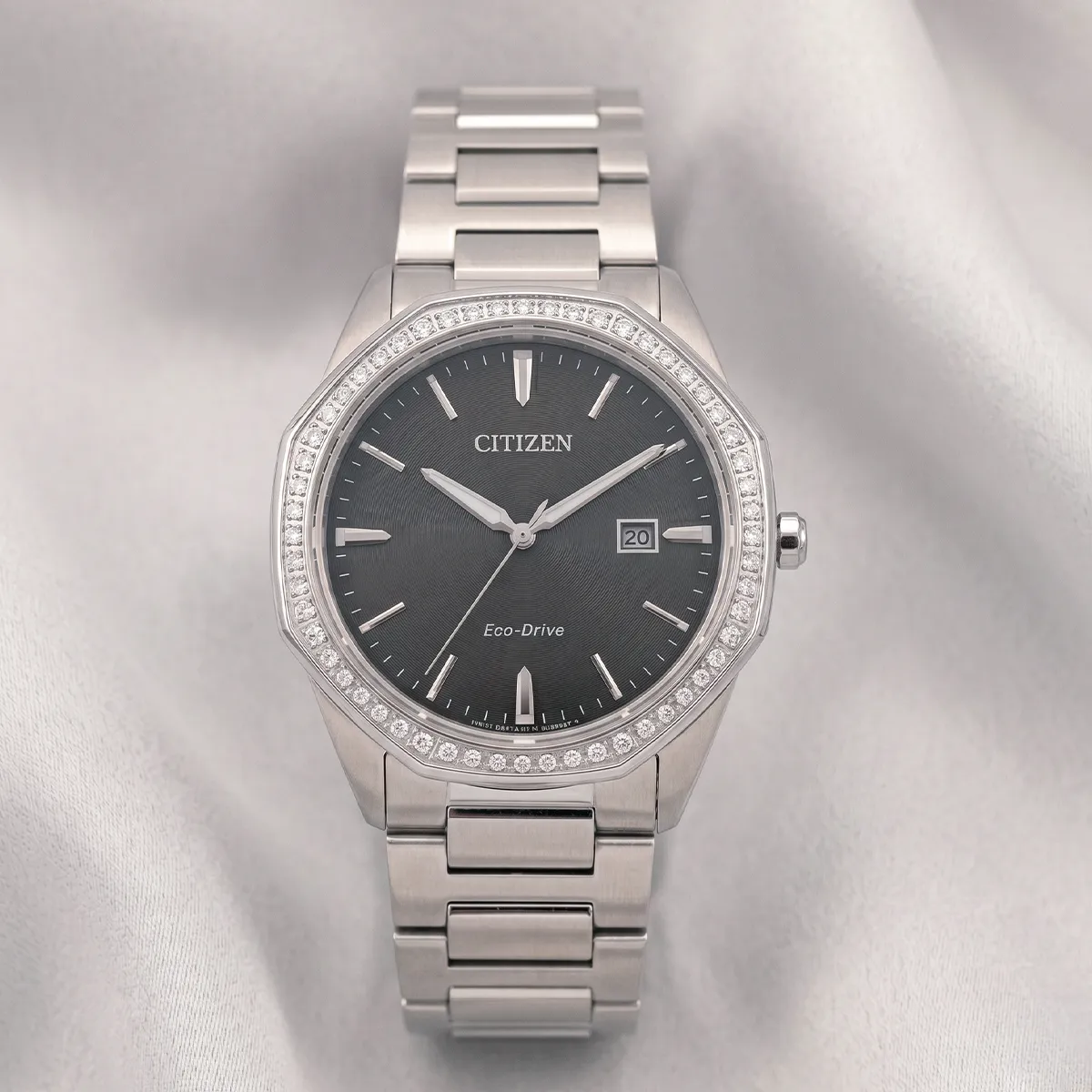 Citizen Eco-Drive watch with diamond bezel on gray fabric. Shop watches at Georgetown Jewelers, Wood Dale, IL.