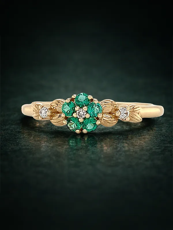 A gold ring with a large green gemstone and diamond accents on a dark background.