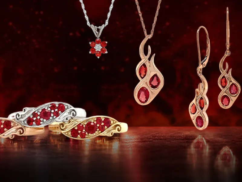 A collection of ruby and diamond jewelry, including rings, earrings, and necklaces, displayed on a dark red background.
