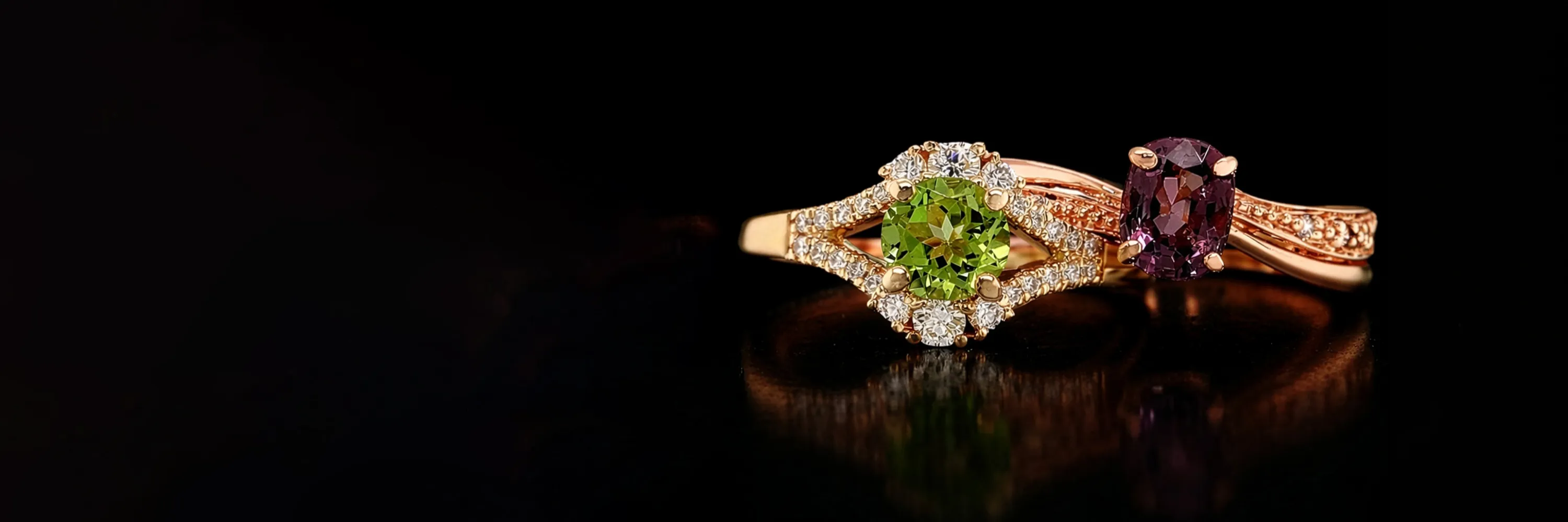 Two gemstone rings with green and purple stones on a black background.