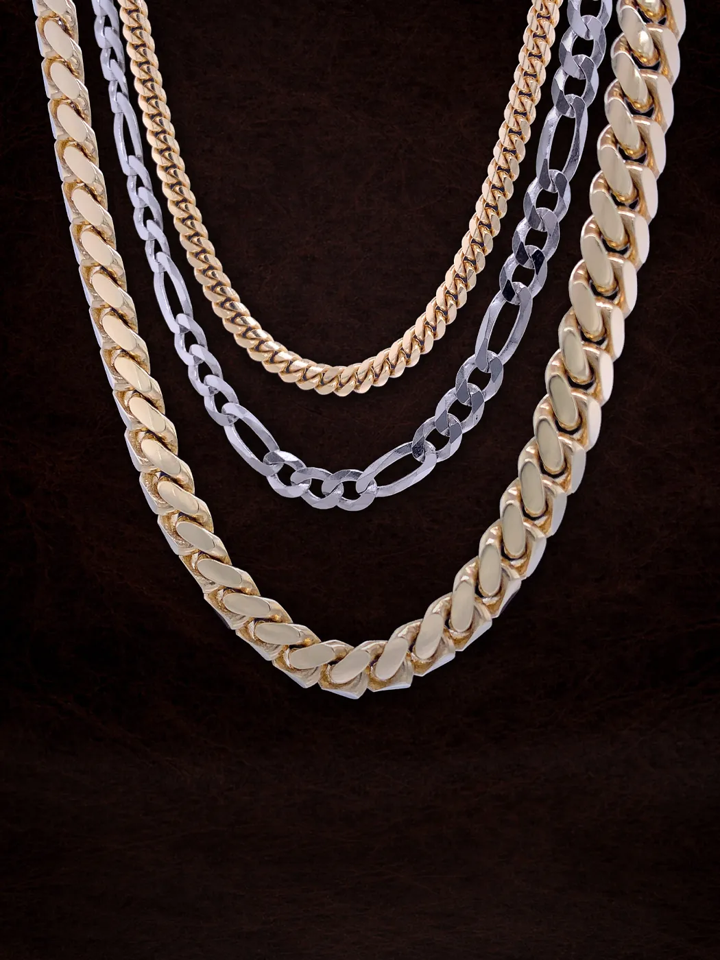Gold and silver chains displayed against a dark background.