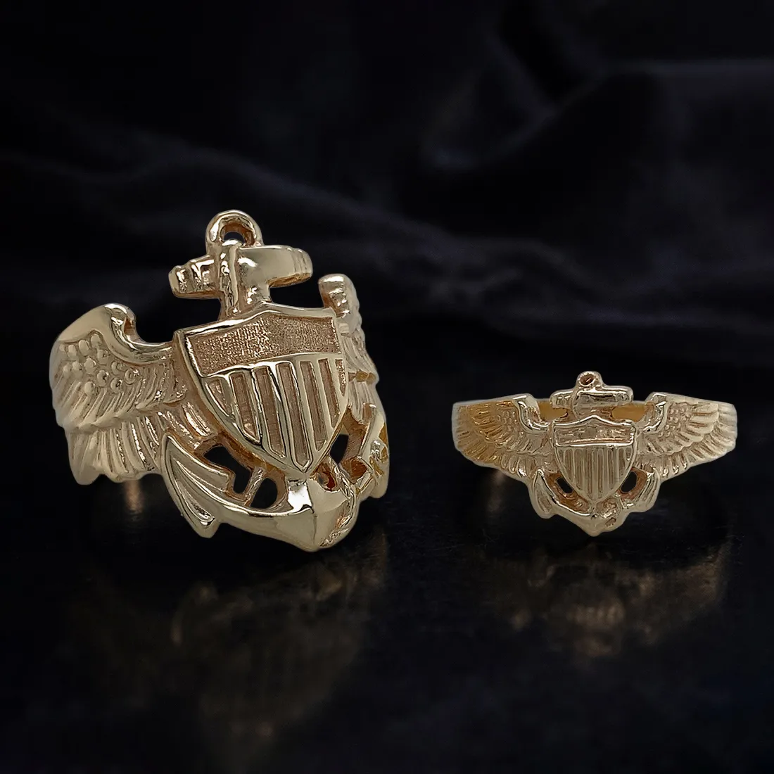 Two gold rings with military insignia on a dark background.