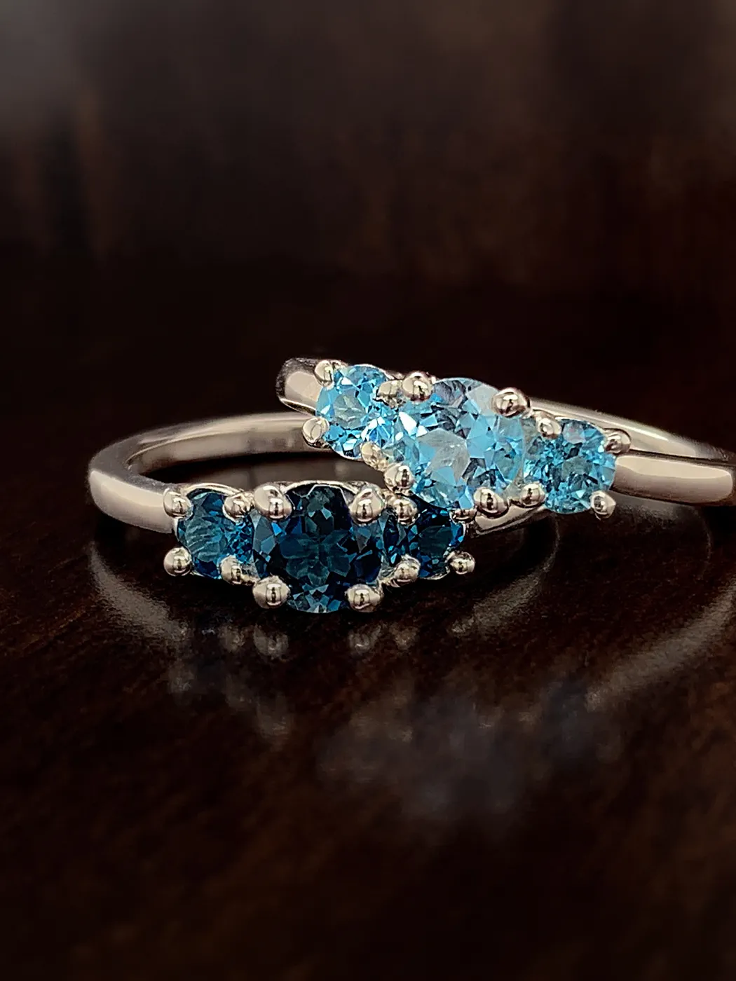 Two silver rings with blue gemstones on a dark surface.