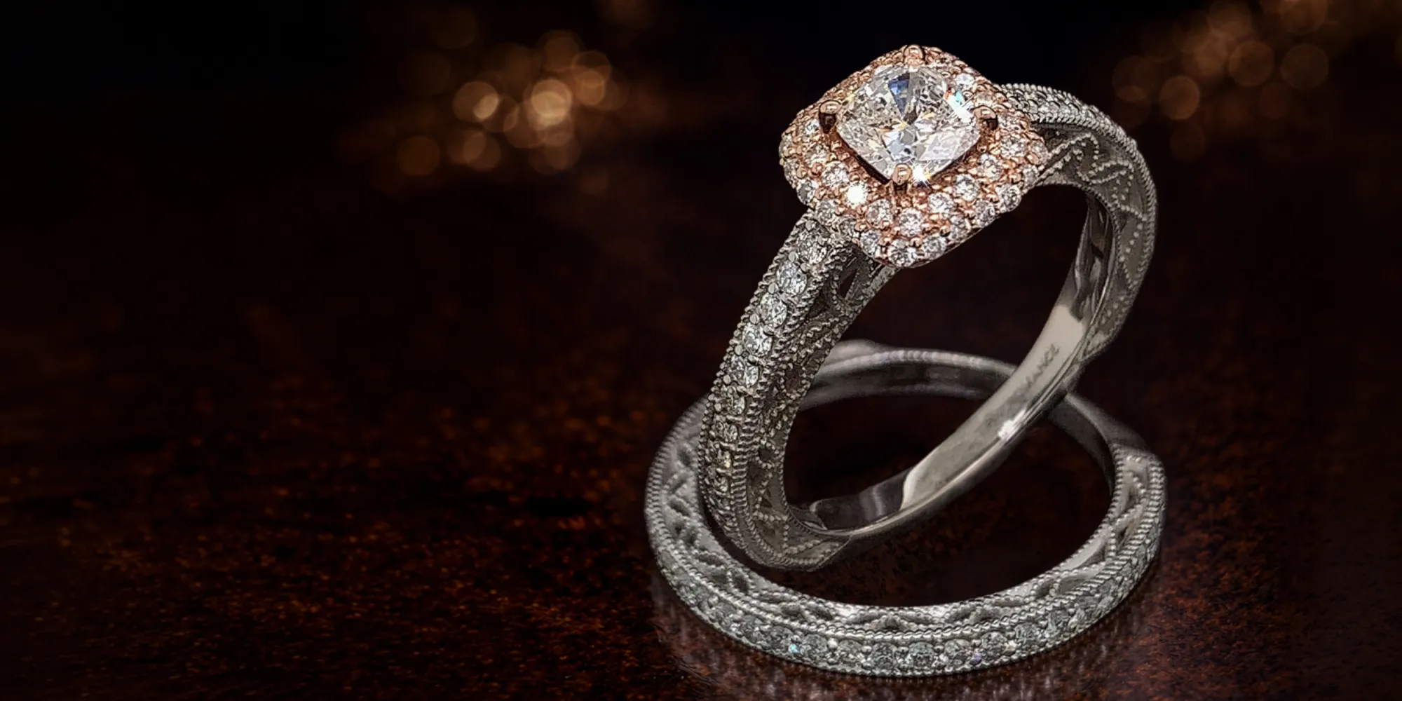 Two intricately designed rings with diamonds on a dark background.
