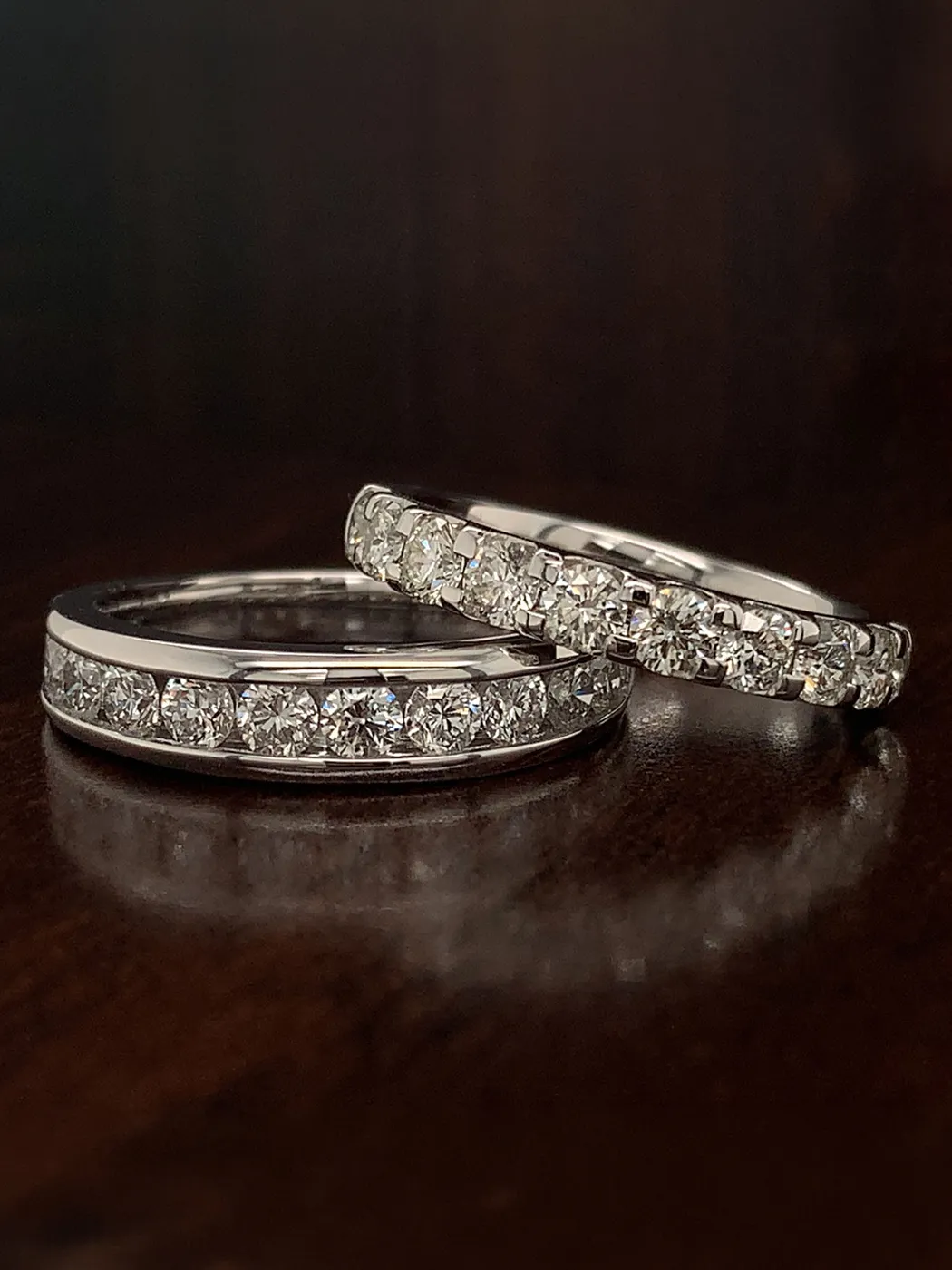 Two diamond-studded rings on a dark surface.