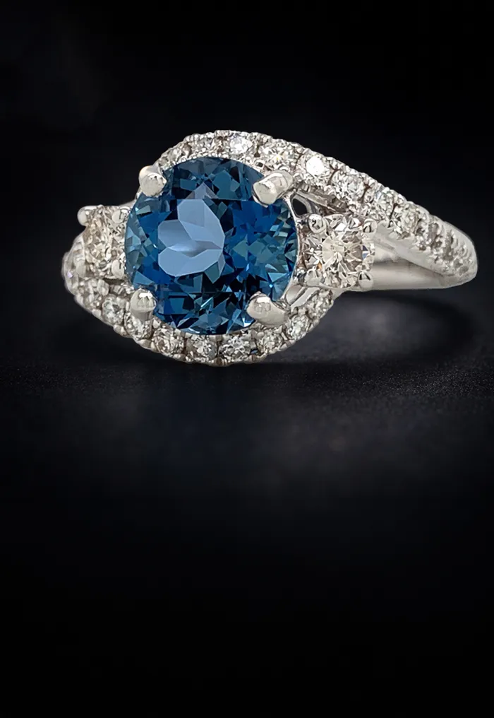 Elegant ring with a blue gemstone and diamond accents on a dark background.