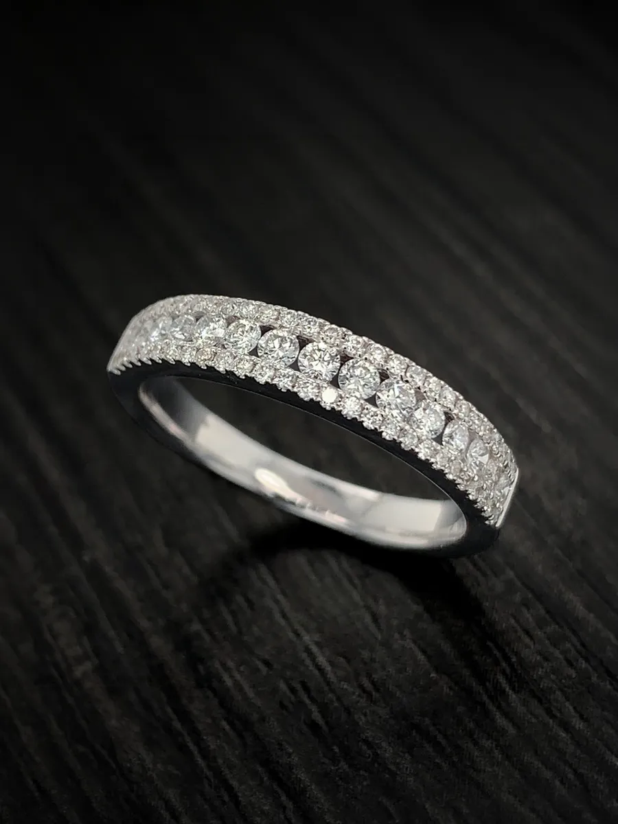 Diamond ring with two rows of small diamonds on a dark background.