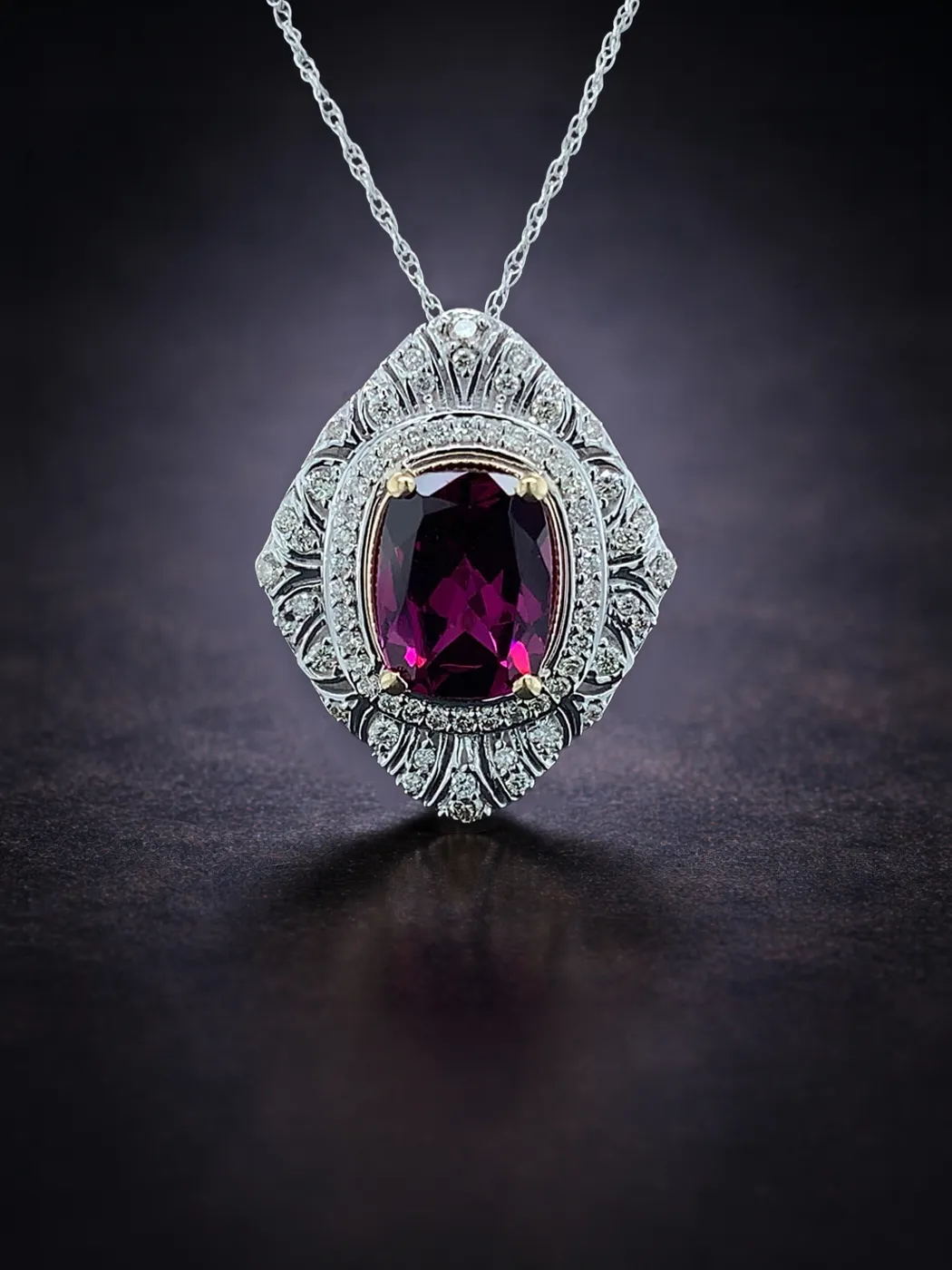 Elegant pendant with a deep red garnet surrounded by diamonds on a silver chain.