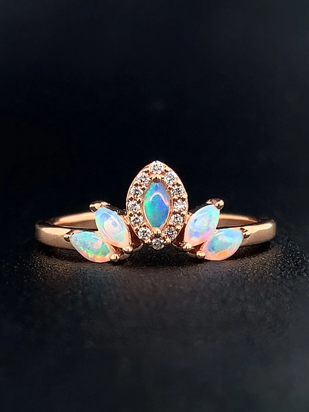 Opal ring with marquise stones on a dark background.