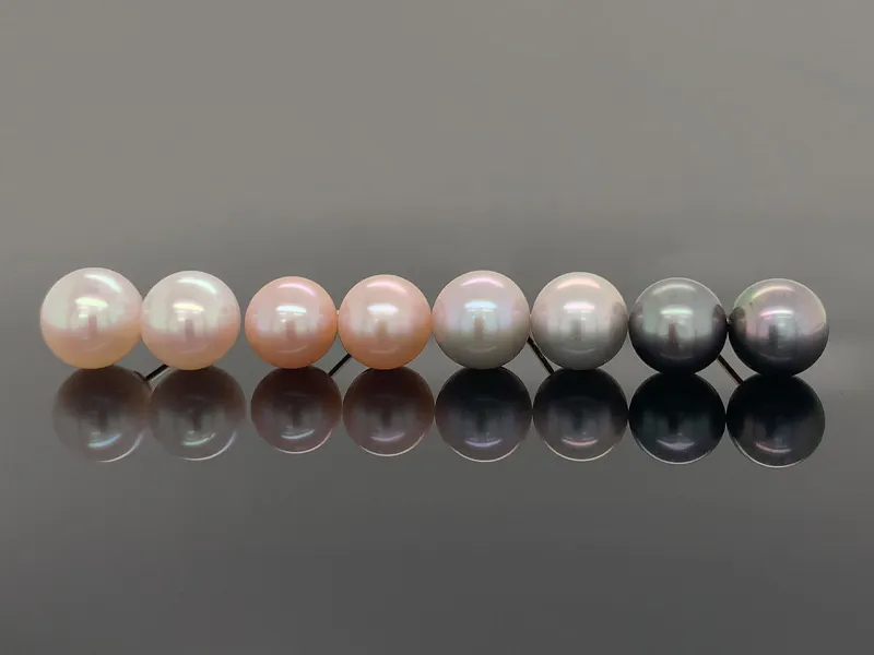 Various colored pearls on a reflective dark surface.