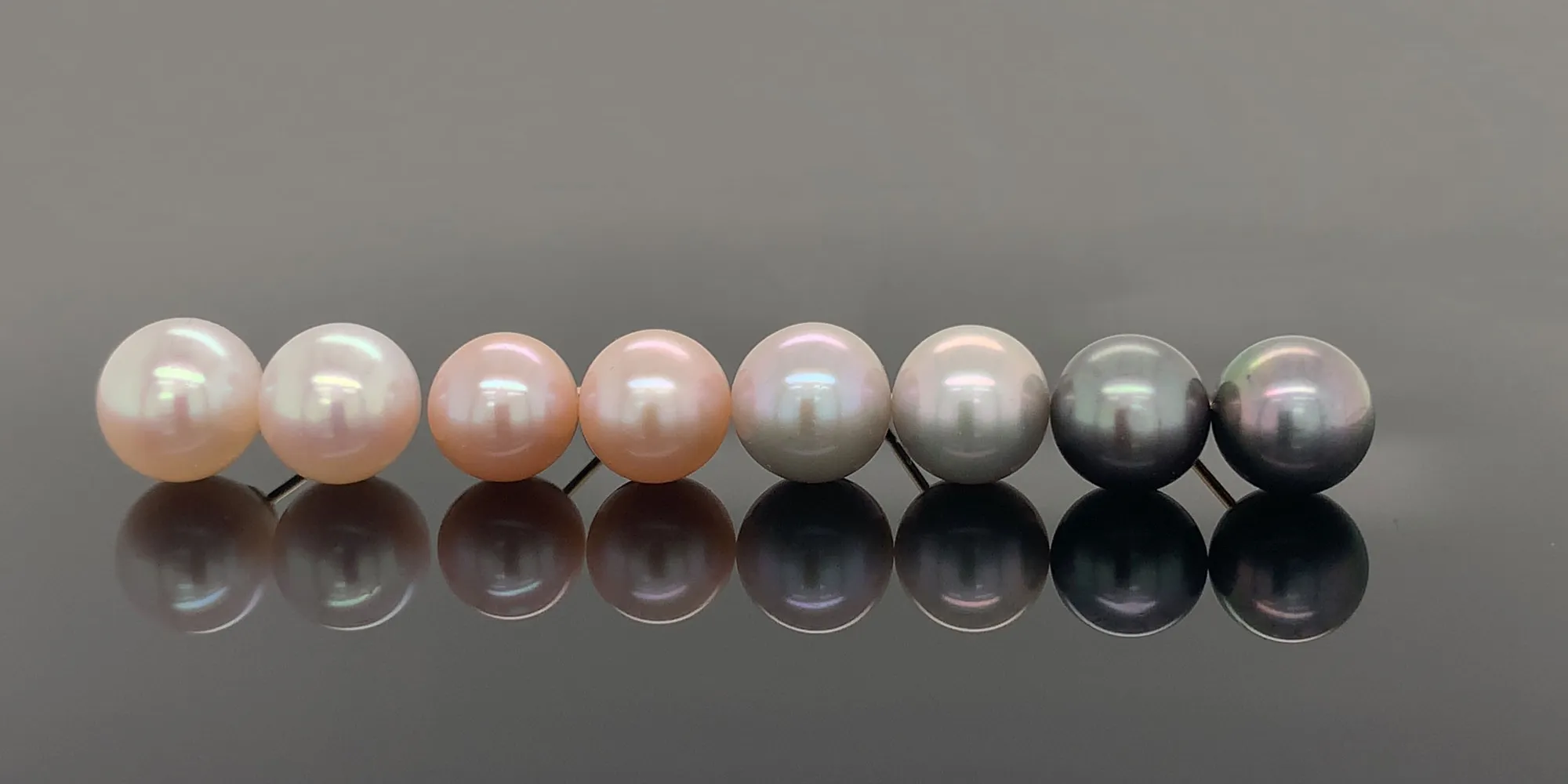 Various colored pearls on a reflective dark surface.