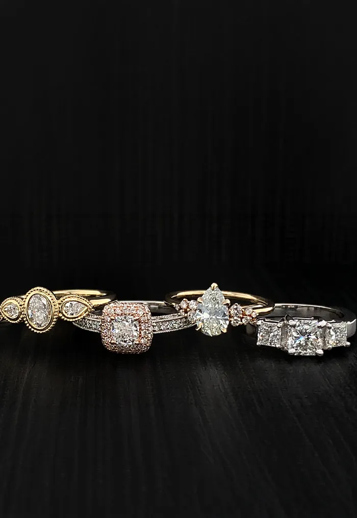 A selection of six elegant diamond engagement rings on a dark background.