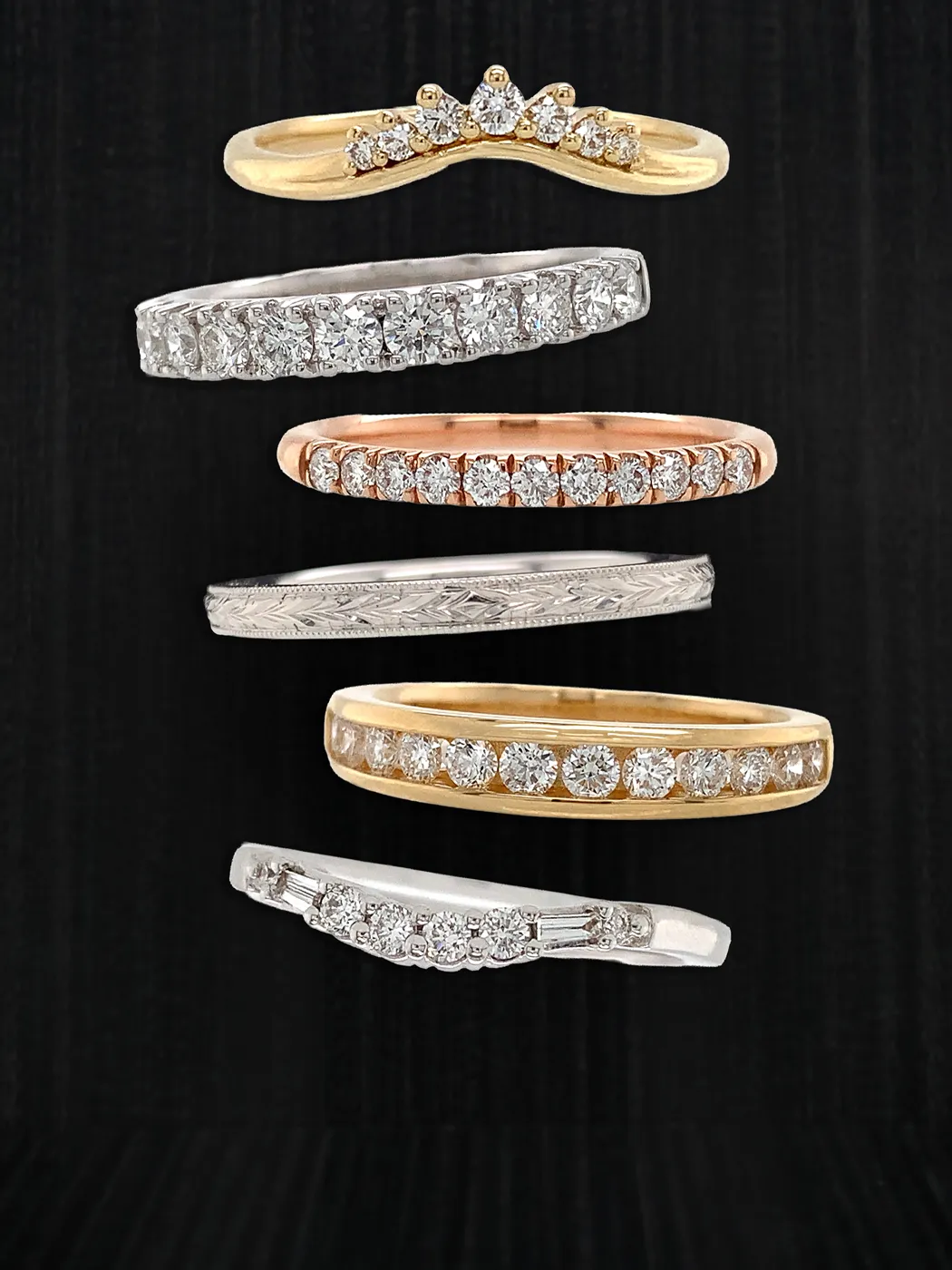 A collection of gold, silver, and rose gold diamond wedding bands on a black background.