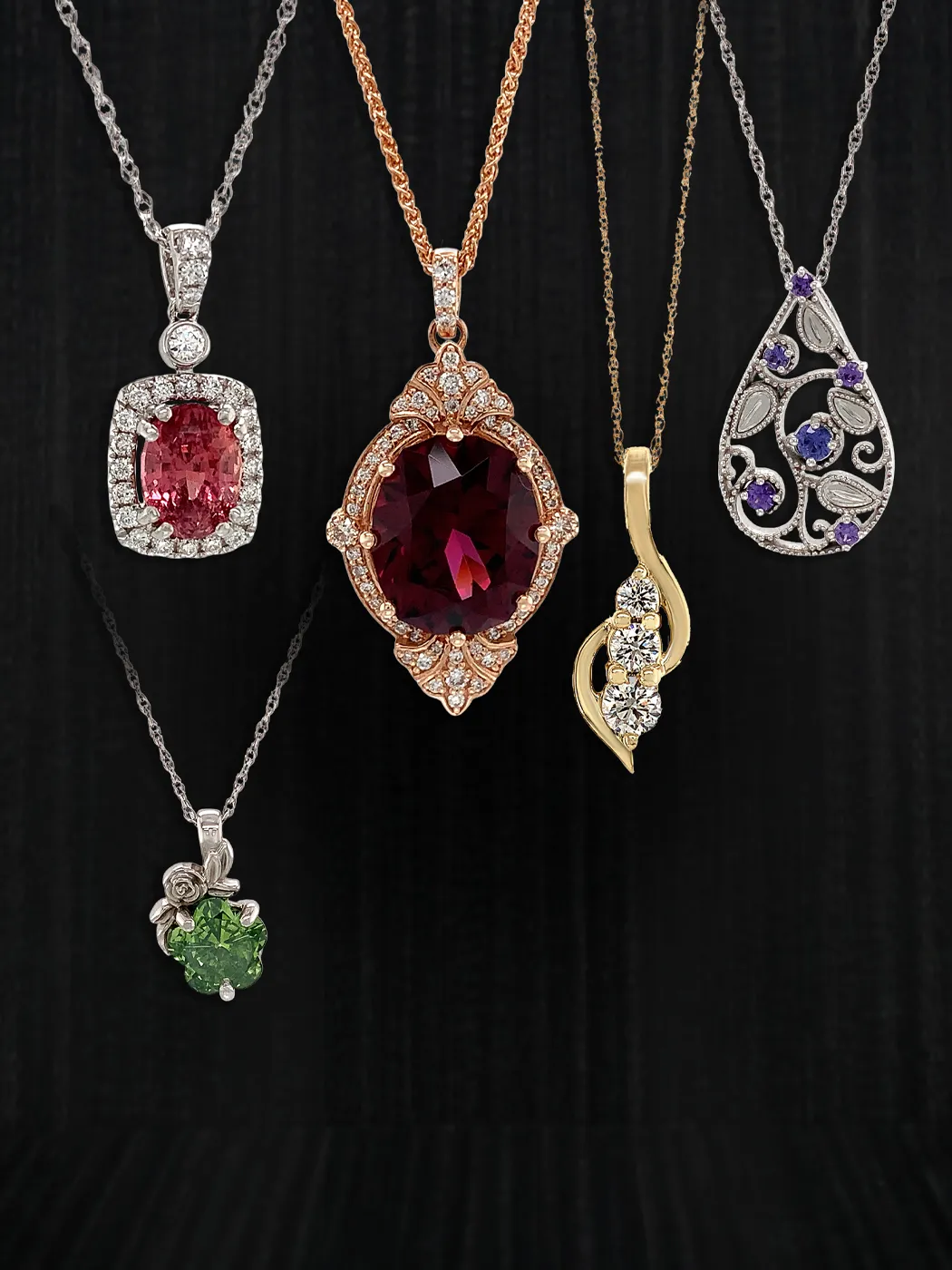 Elegant necklaces with various gemstones on display against a dark background.
