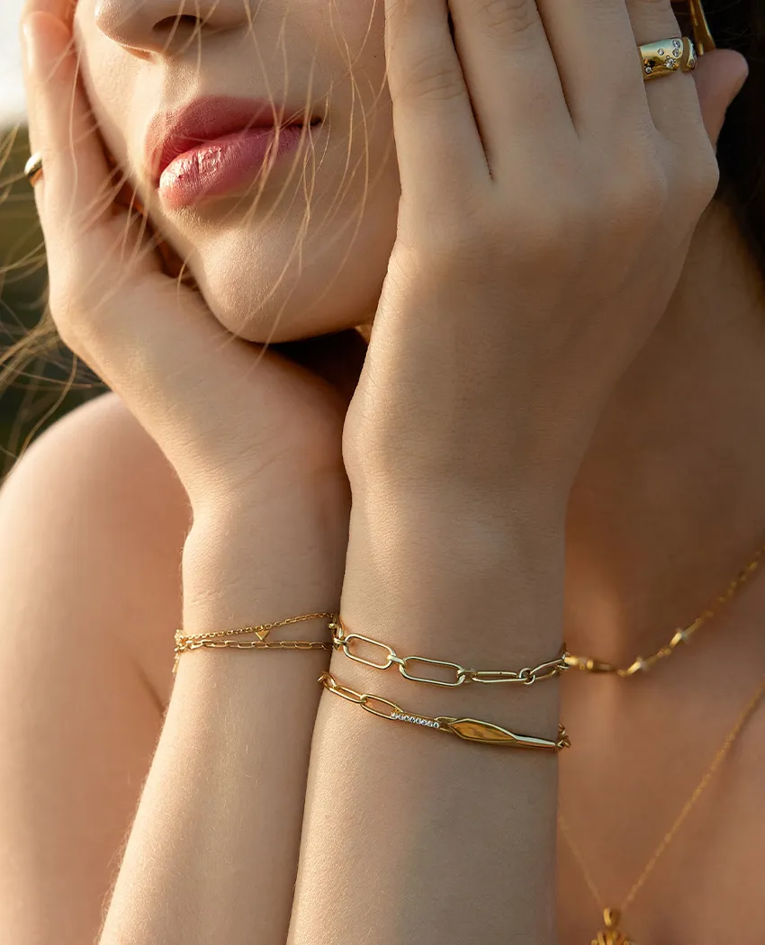 Close-up of a woman's hands adorned with gold bracelets, showcasing elegant jewelry. Click to Shop Bracelets at Golden Gifts Jew
