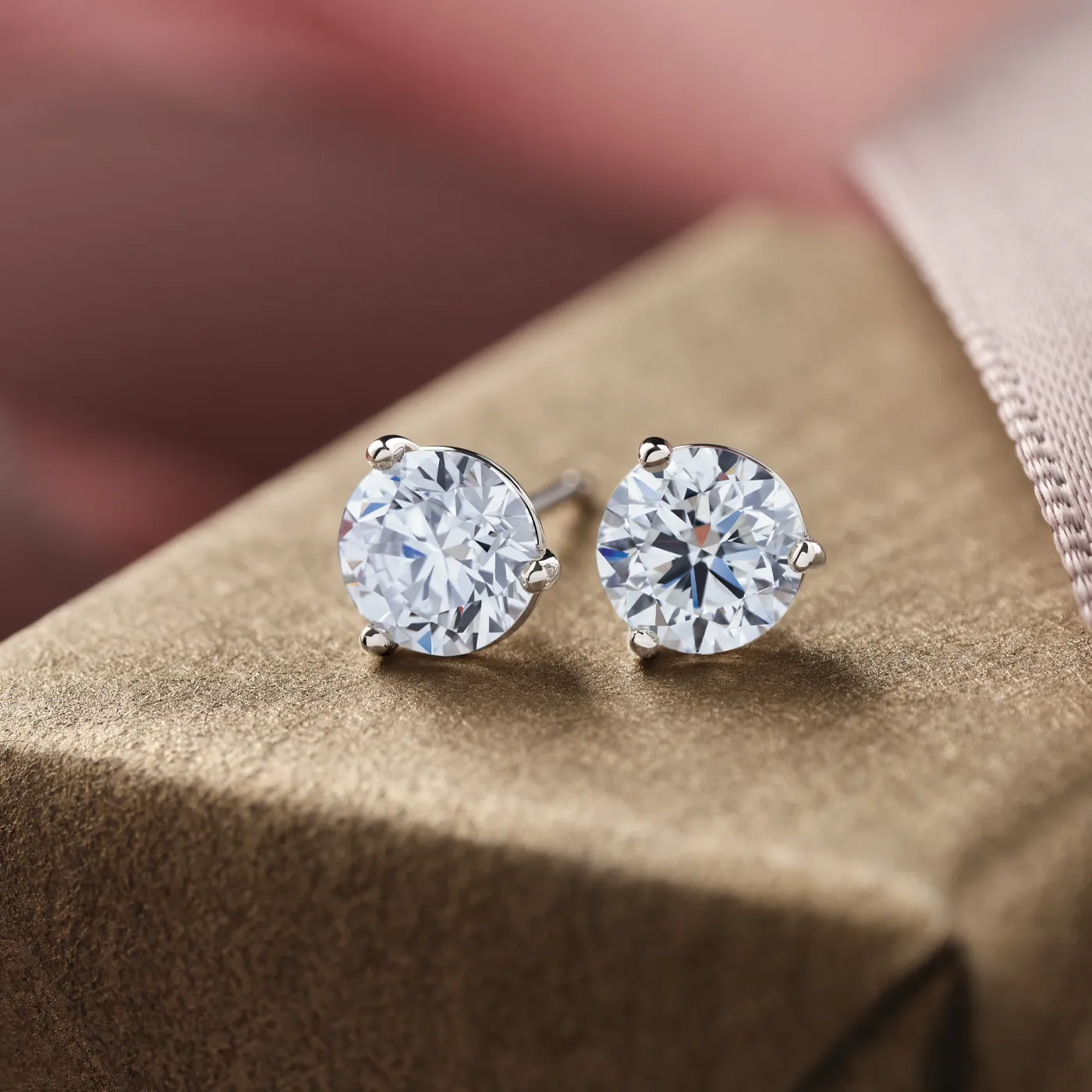 Elegant diamond stud earrings on a textured surface, showcasing their brilliance and classic design.
