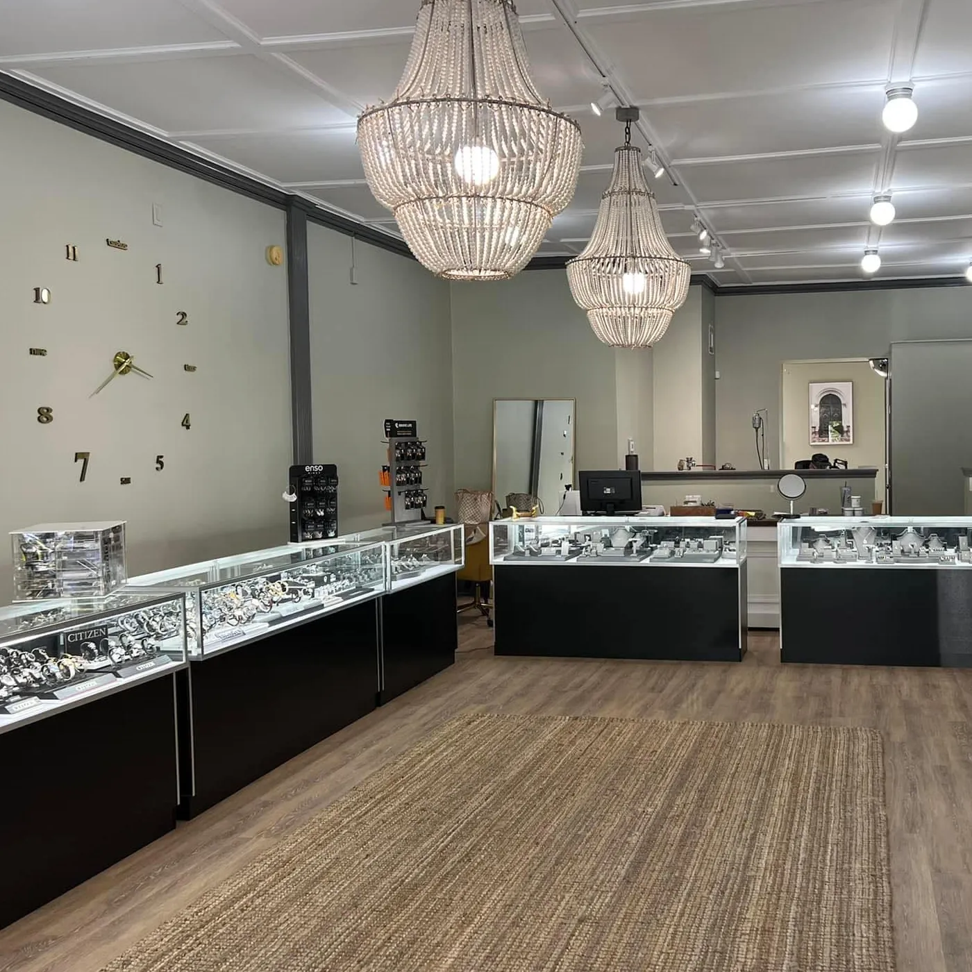 Jewelry store interior with display cases, chandeliers, and a clock, showcasing fine jewelry at Golden Gifts Jewelry in Milford.