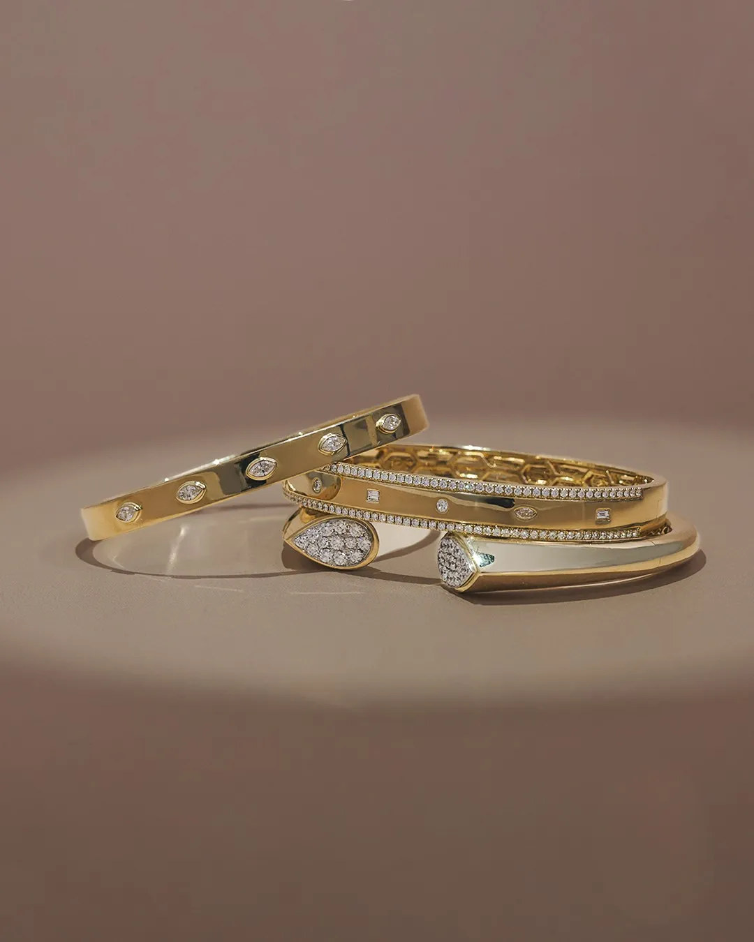 Elegant gold bracelets with diamonds, showcasing fine jewelry from Gray's Jewelers Bespoke. Click to explore more.