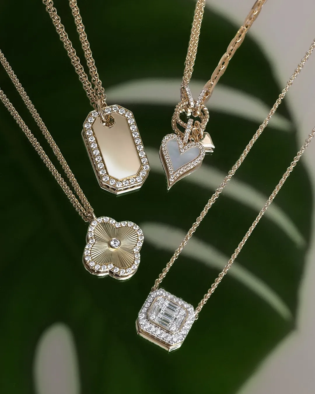Four elegant gold necklaces with various pendants, including a heart and floral design. Shop fine necklaces at Gray's Jewelers.