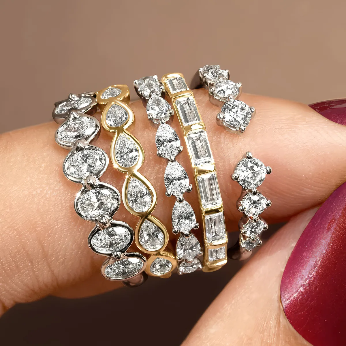 Five diamond rings with various settings and designs displayed on a finger.