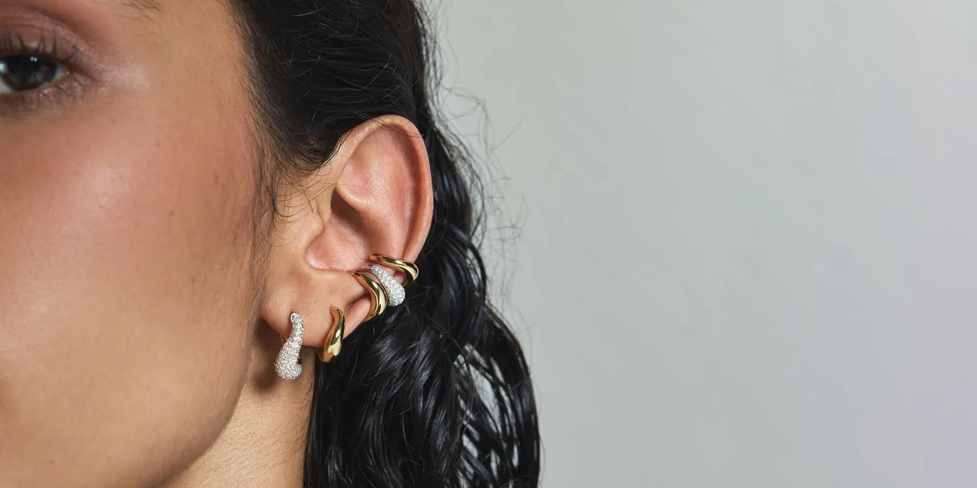 Close-up of an ear with multiple gold and diamond earrings.