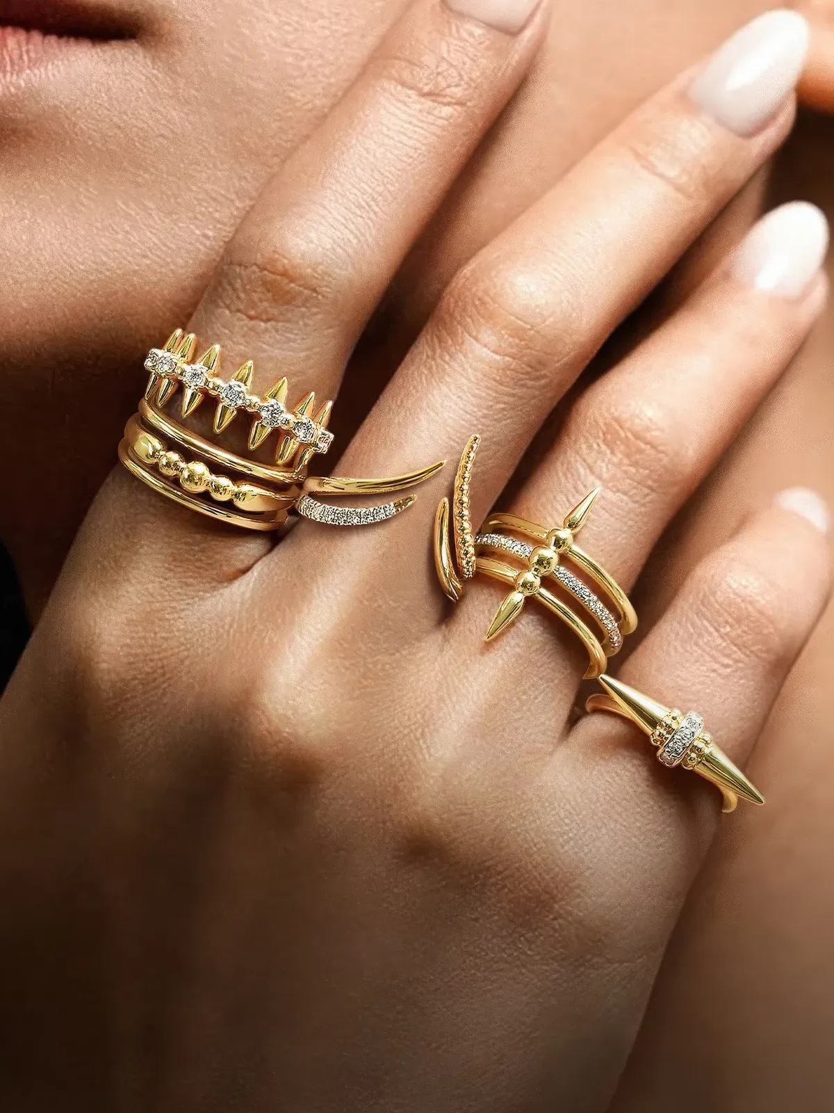 Hands adorned with multiple gold rings featuring spikes and diamonds.