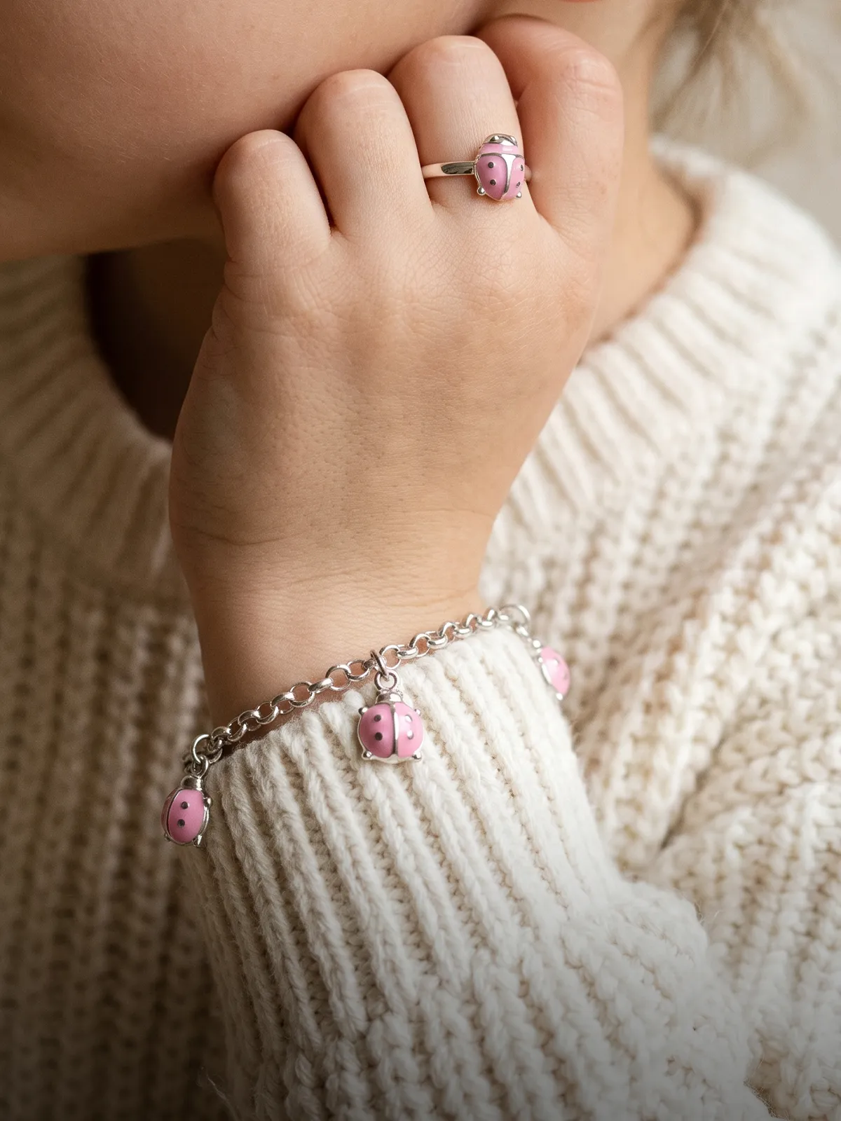Two silver hoop earrings with diamond accents on a soft pink fabric background.
