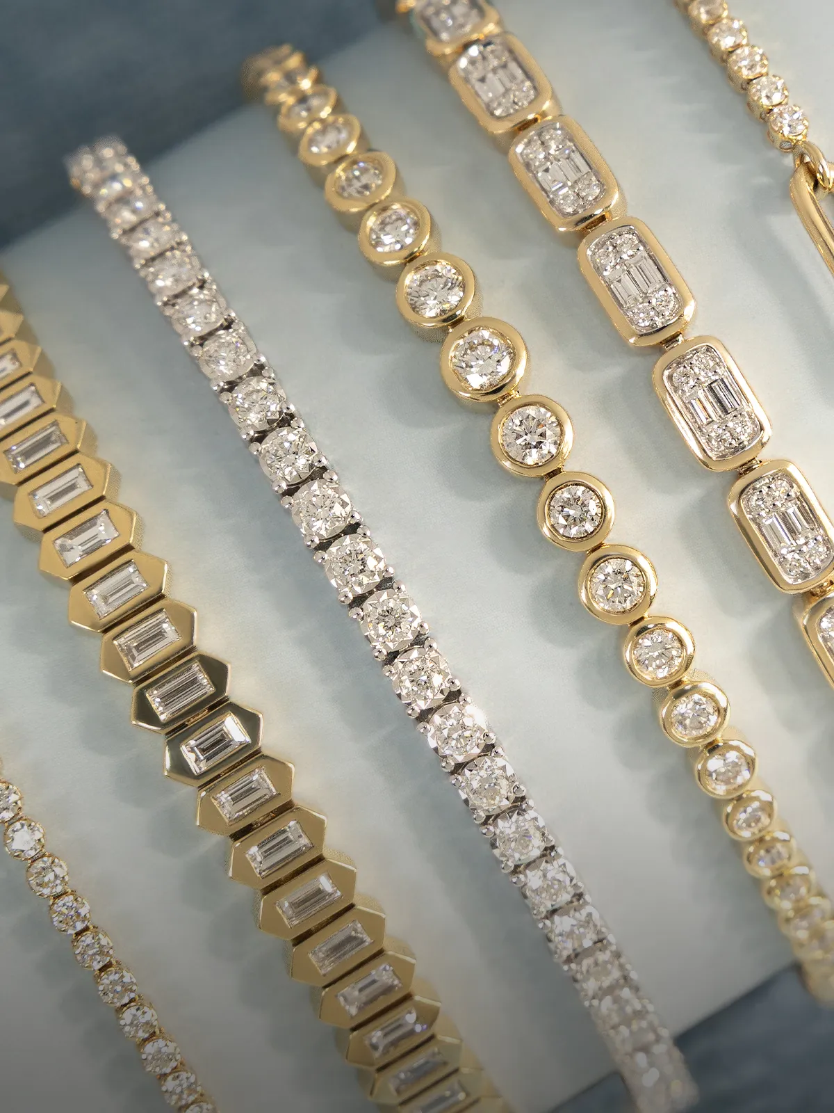 A collection of gold and diamond bracelets displayed on a light background.