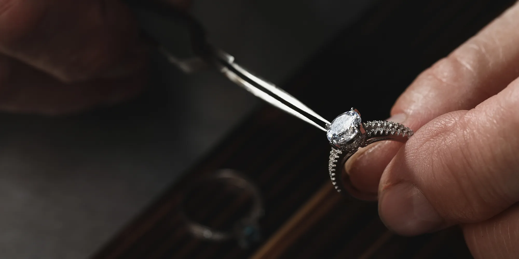 A jeweler uses pliers to adjust a diamond ring.