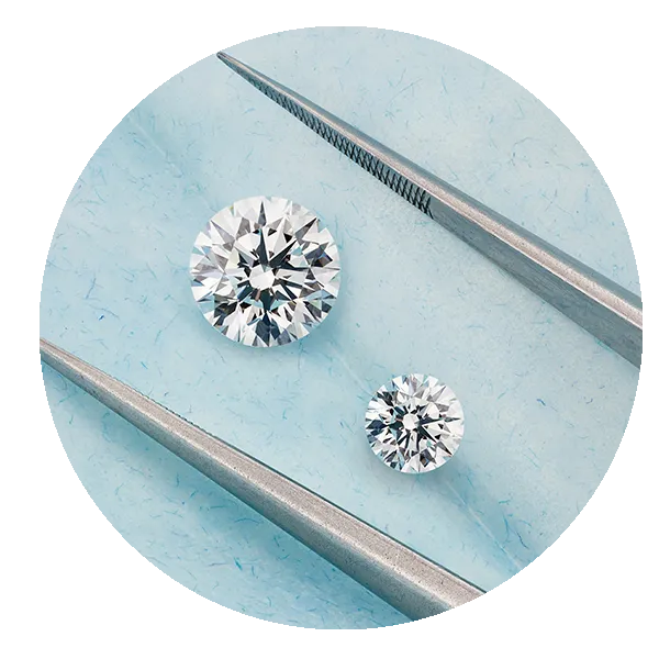 Two round brillinat diamonds side by side with jewellers tweezers