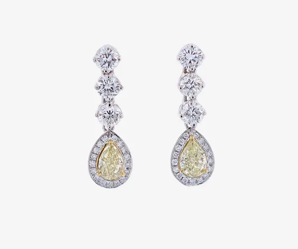 A pair of yellow diamond drop earrings on grey brackgound